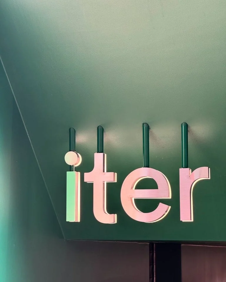 iter 외관 — 다크 그린 벽과 메탈릭 로즈 사인
